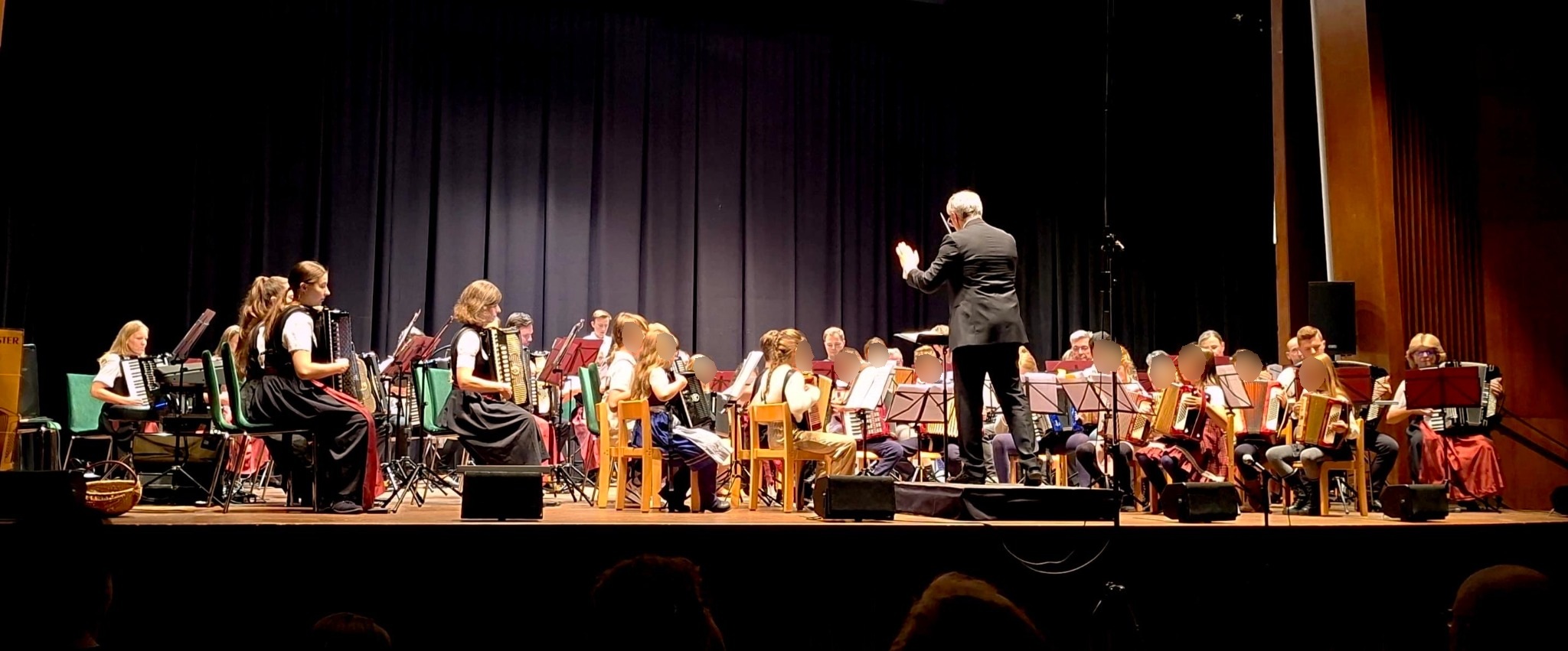 Das Gemeinschaftsorchester der Akkordeonorchester München mit Kindern, Jugendlichen und Erwachsenen auf der Bühne der Alten Kongresshalle, davor Dirigent Stefan Fußeder.