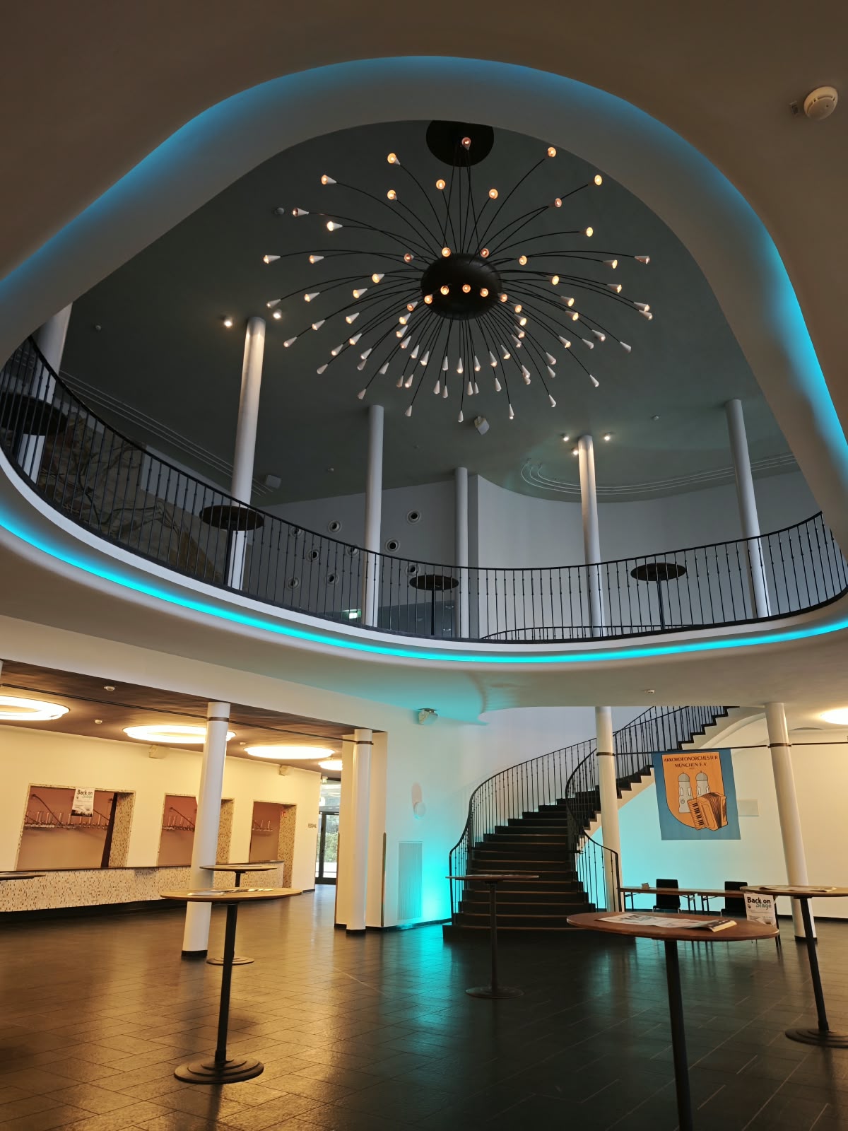 Das Foyer der Alten Kongresshalle München mit großem Sternleuchter, geschwungener Galerie und Treppe; an der Treppe hängt das Banner mit dem Wappen der Akkordeonorchester München.